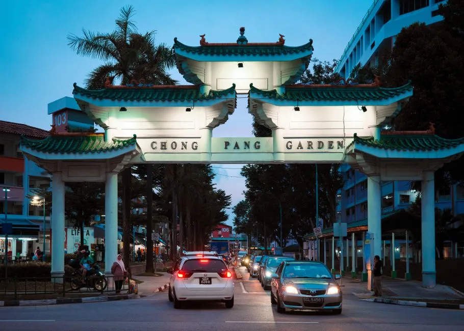 Chong Pang Garden entrance gate illuminated at dusk with traffic and pedestrians in Singapore.