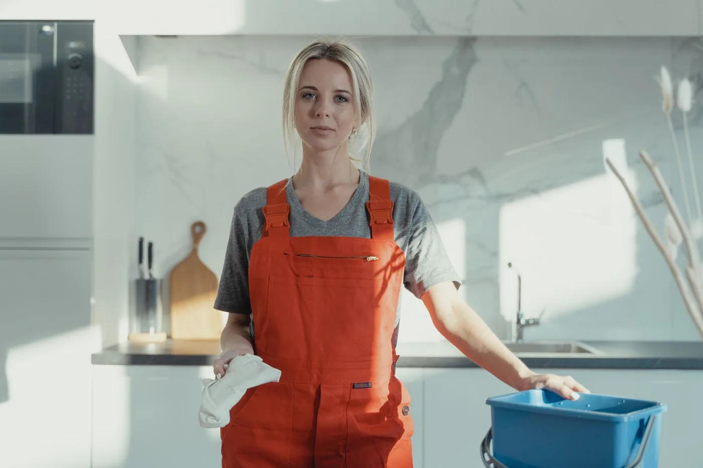 Professional cleaner with supplies in a spotless modern kitchen. Photo by Tima Miroshnichenko on Pexels