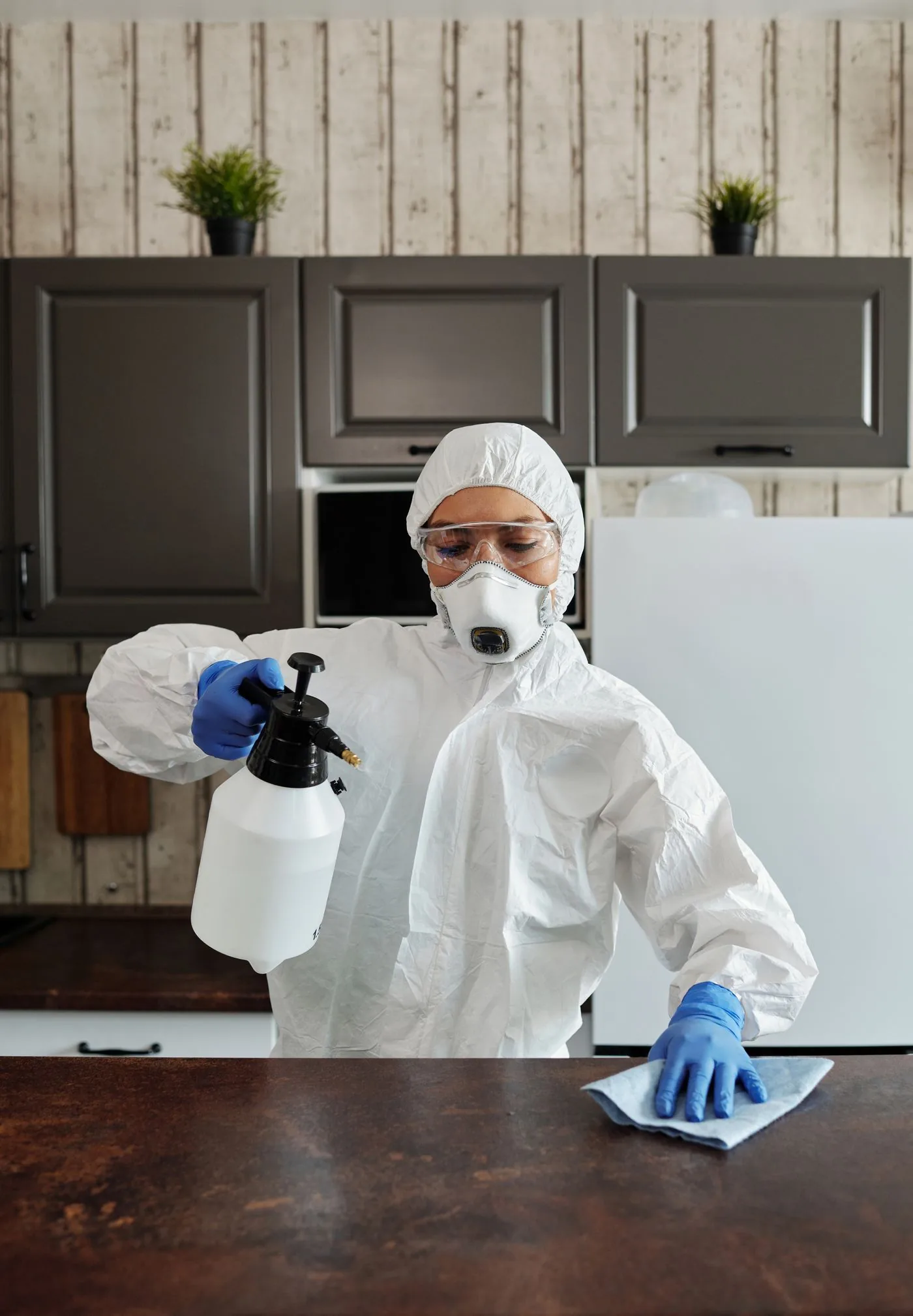 Technician in PPE sanitising a commercial surface for compliance