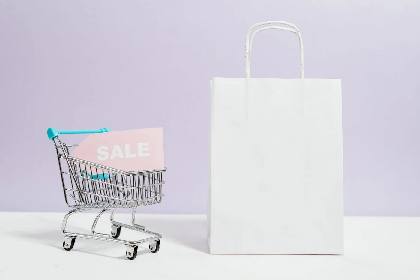 Shopping cart with a sale tag next to a retail bag. Photo by www.kaboompics.com on Pexels