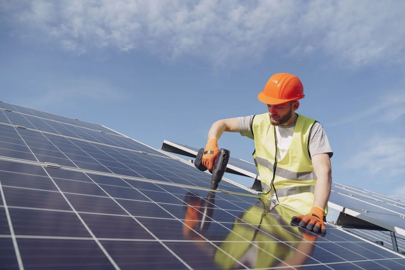 Technician installing solar panels with a power tool on a roof. Photo by Gustavo Fring on Pexels