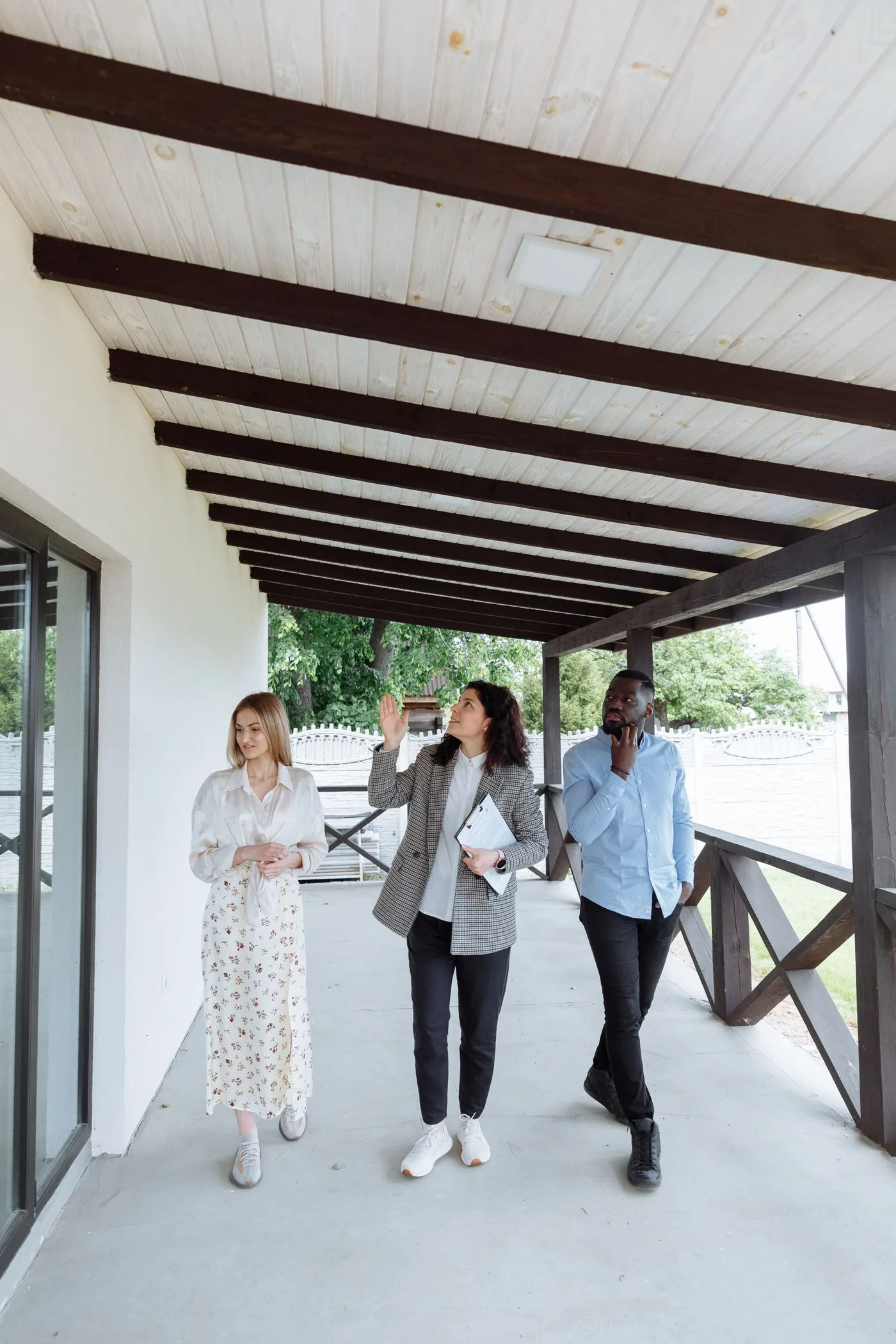 Real estate agent with clients viewing a property on the porch. Photo by Thirdman on Pexels