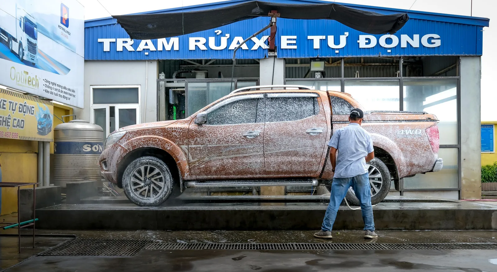 A pickup truck being cleaned at a modern automated car wash facility with a worker present in Singapore. Photo by Quang Nguyen Vinh on Pexels