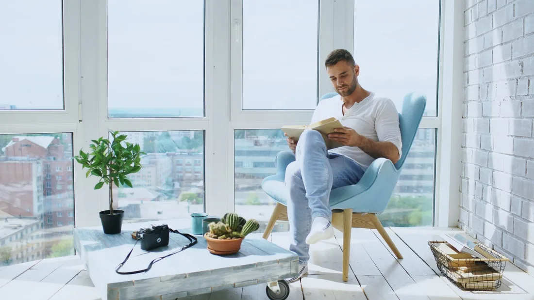 Person reading in a bright modern apartment with large windows and city view in the UK. Photo by Vitaly Gariev on Pexels