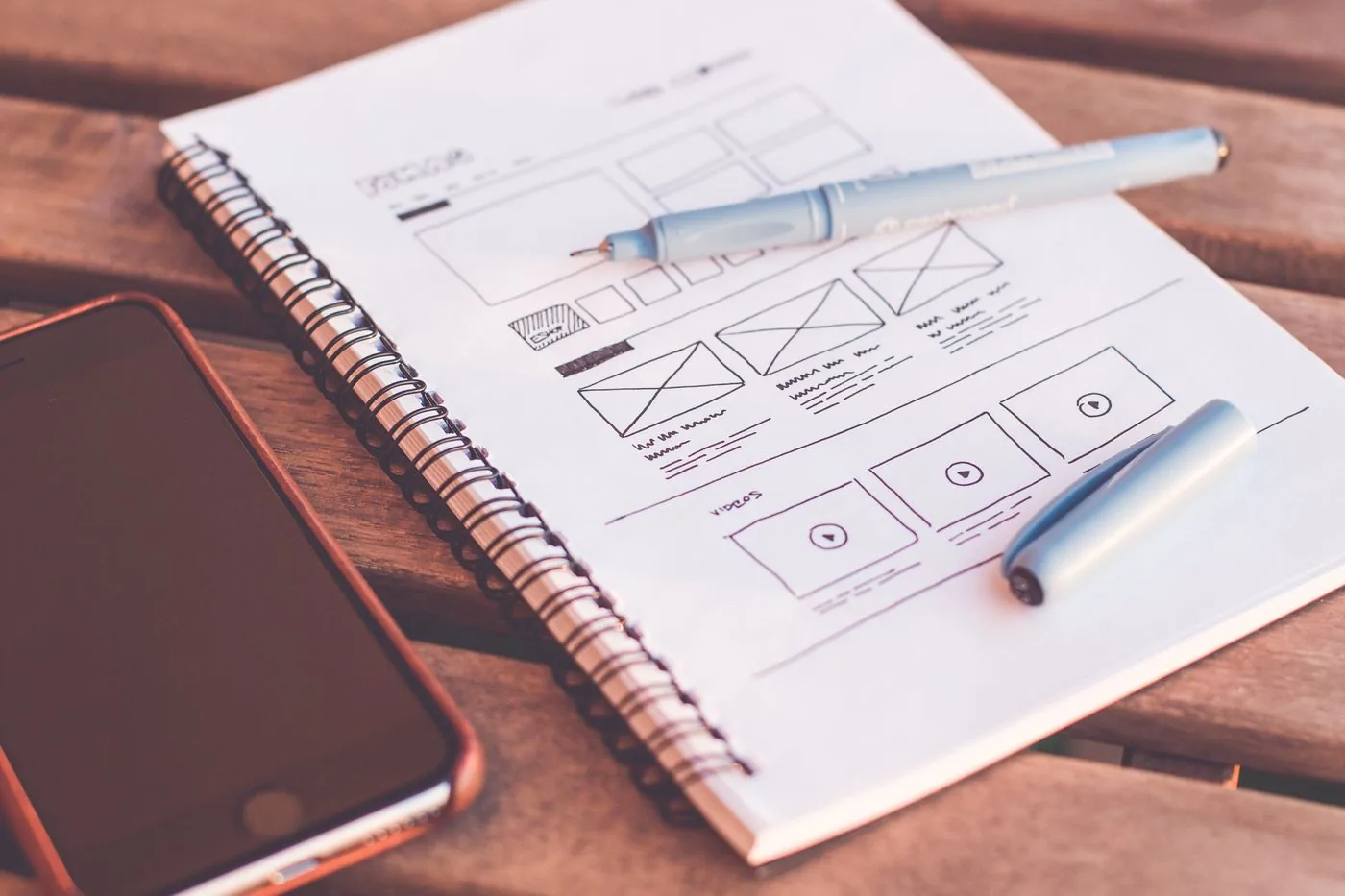 Landing page wireframe sketches next to a smartphone